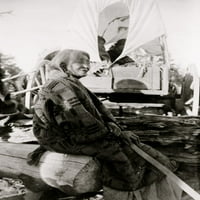 Stara Indijanka iz plemena Navajo koja sjedi na balvanu, u pozadini natkrivenog vagona. Ispis plakata